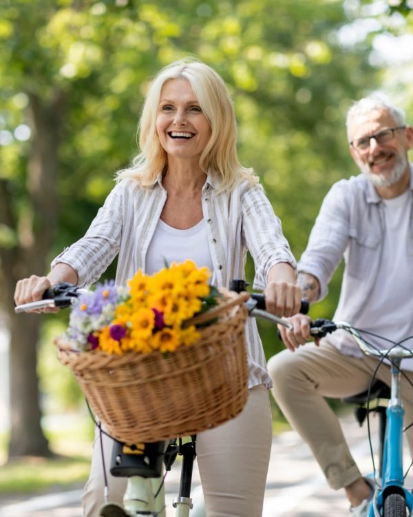 Happy cheerful mature couple enjoying bike ride in summer park, positive senior spouses having fun while riding retro bicycles together, racing with each other and laughing, free space